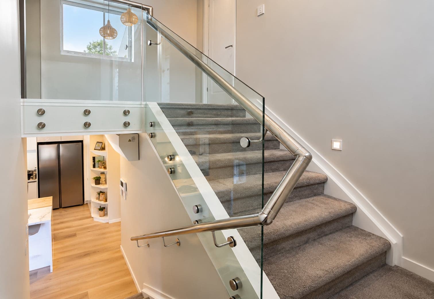 Silver handrail and glass panels beside carpeted stairs