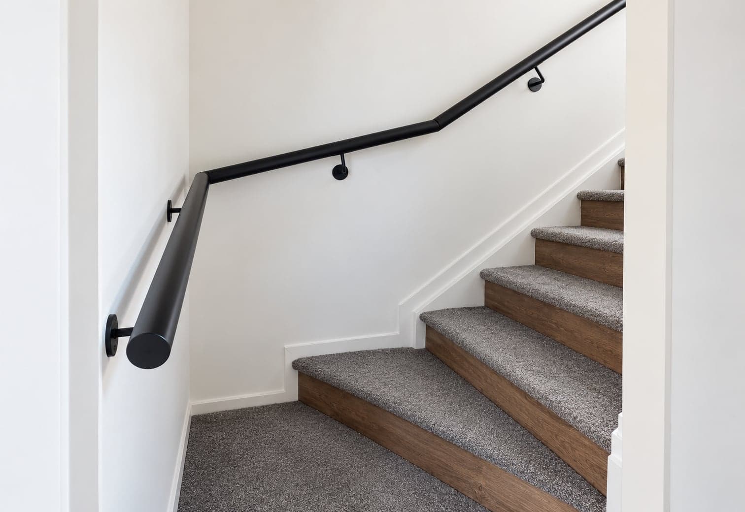 Black wall-mounted handrail following an indoor staircase