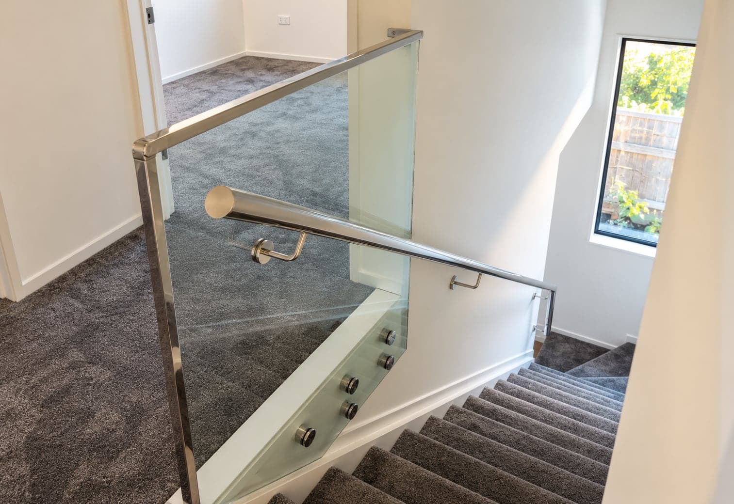 Silver handrail with framed glass balustrade beside stairs