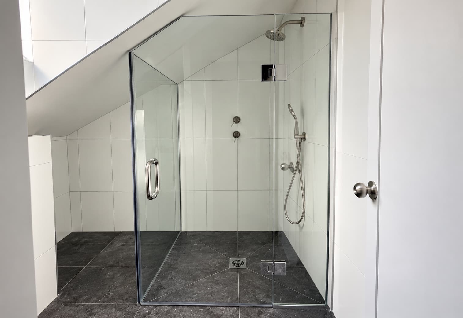 Glass shower enclosure fitted beneath a sloped attic ceiling