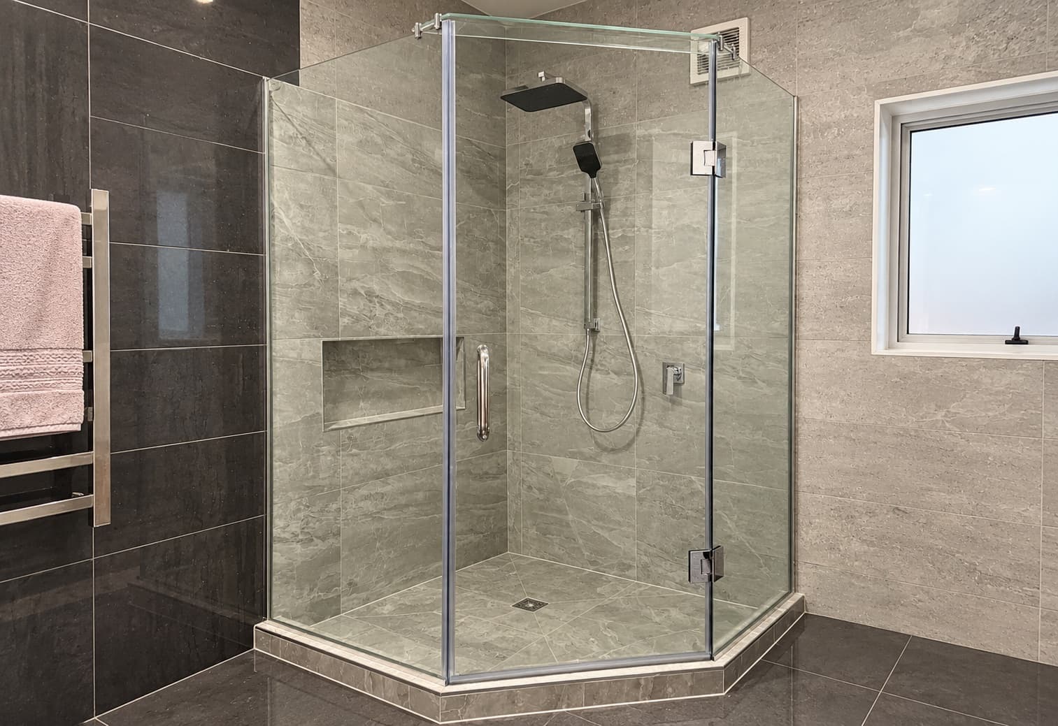 Glass corner shower in a modern grey tiled bathroom