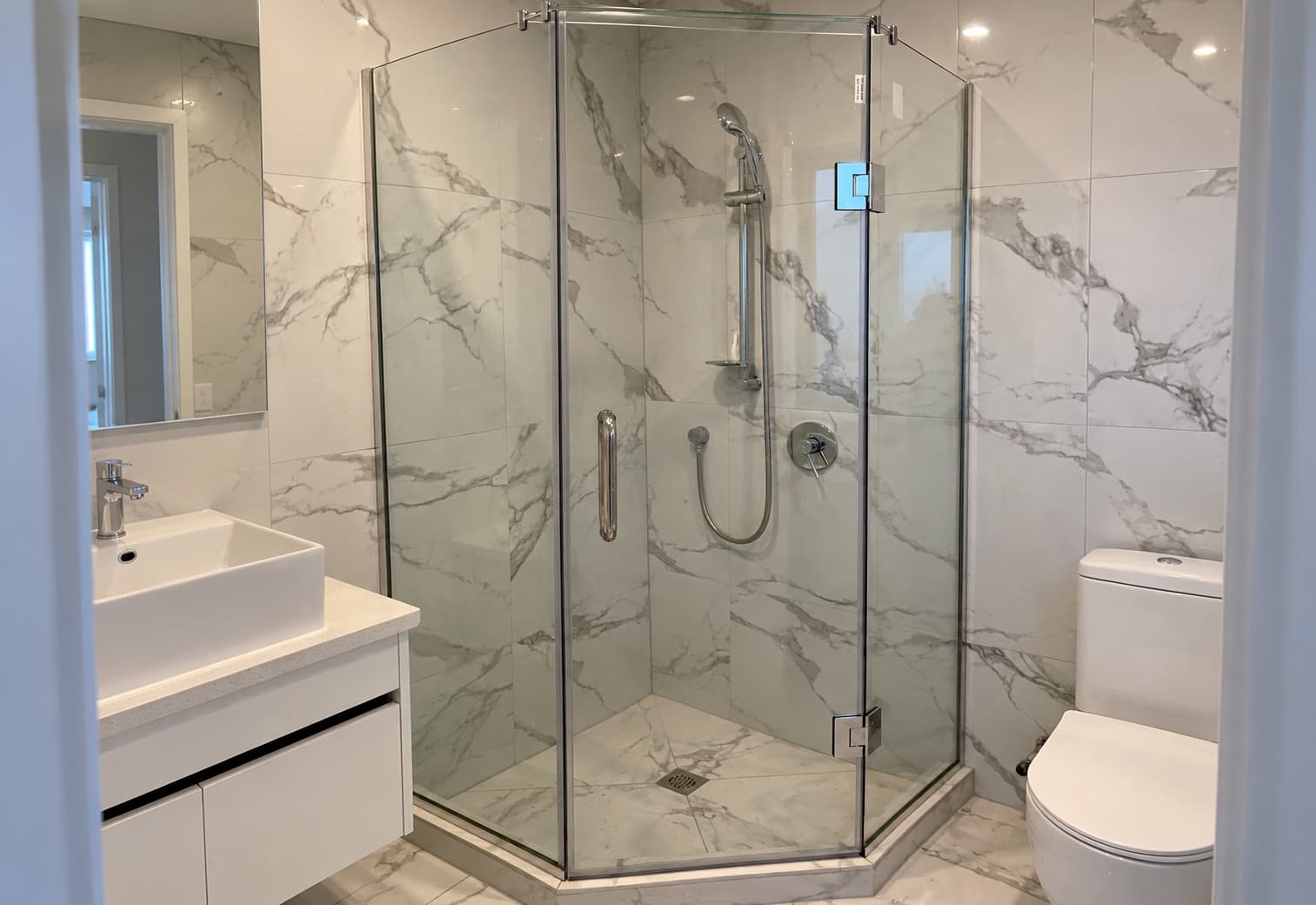 Glass shower enclosure in a marble tiled bathroom