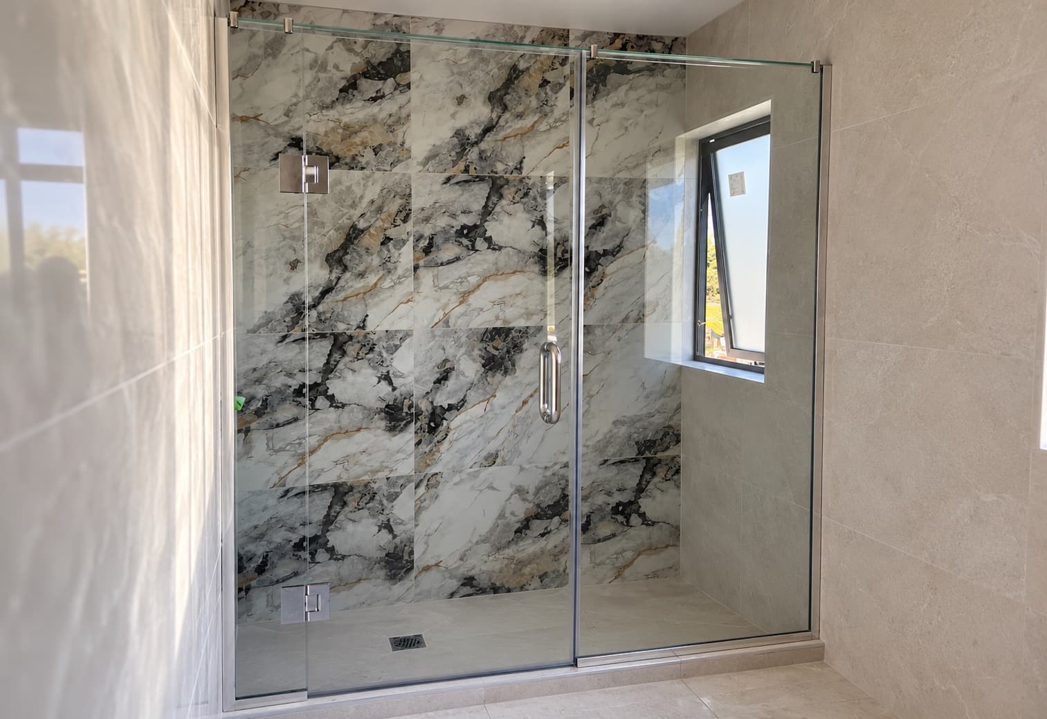 Walk-in glass shower with marble feature tiles
