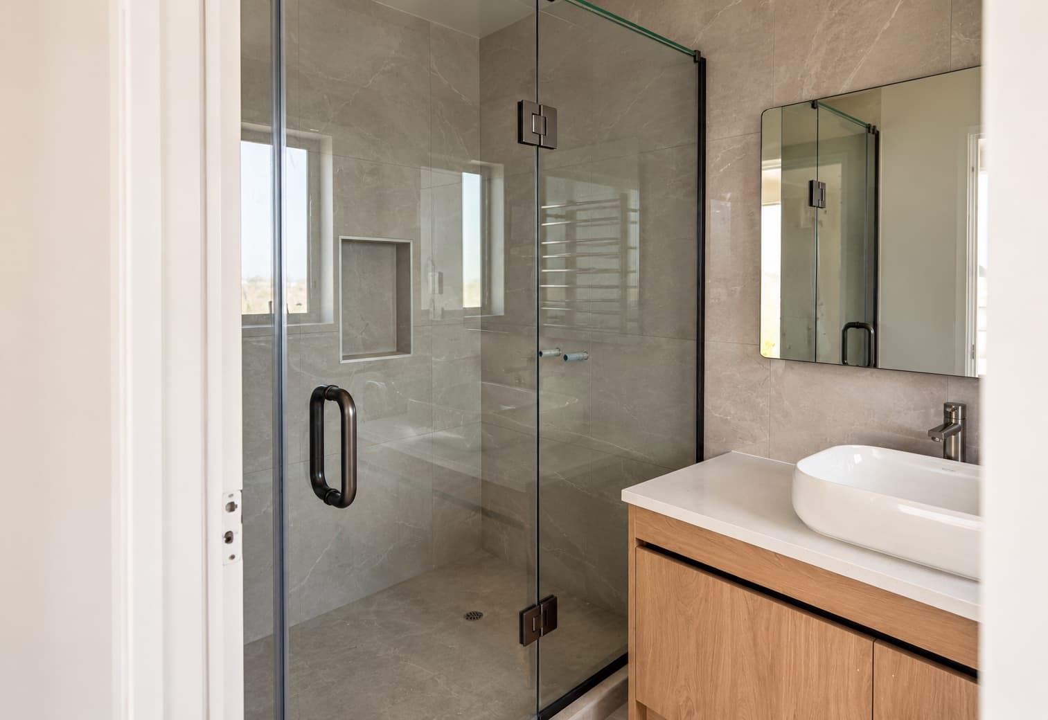 Glass shower enclosure in a modern neutral bathroom